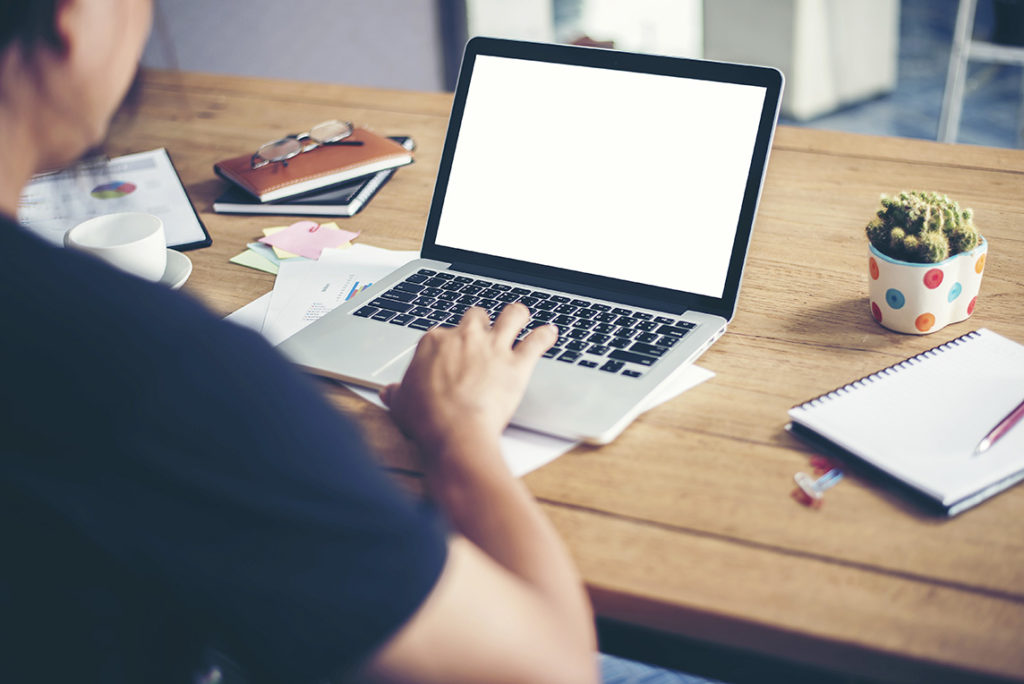 man hands typing working with laptop on wooden desk.